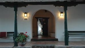 A covered entrance with a stone staircase leading to an interior hallway, flanked by two benches and a potted plant. - Hacienda de Molinos (Molinos)
