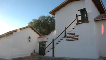 A white building with a staircase leading to a door marked "HOTEL RESTAURANTE COCINA DE AUTOR."
