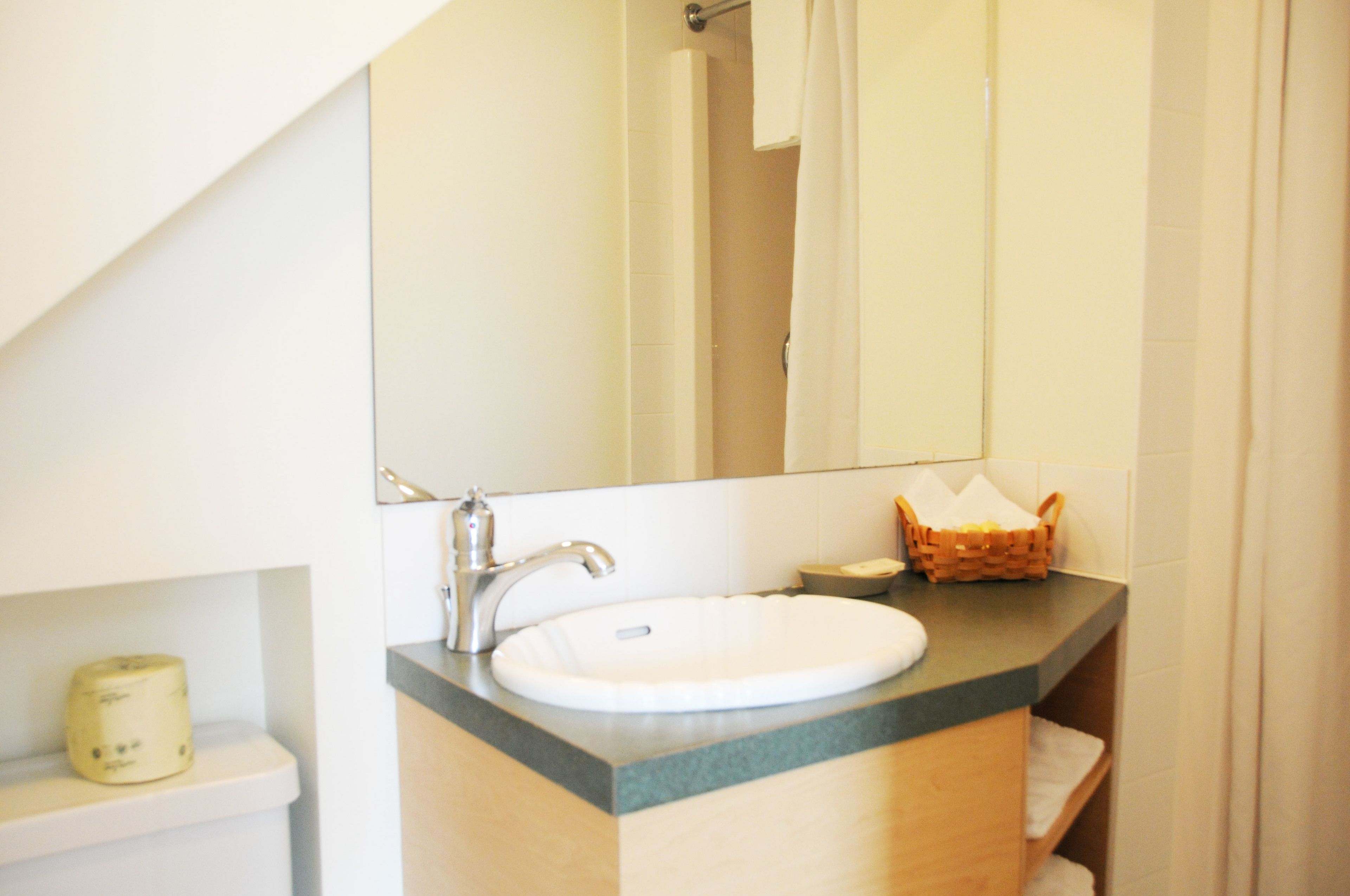 A bathroom with a white sink, a mirror, and a wooden vanity.