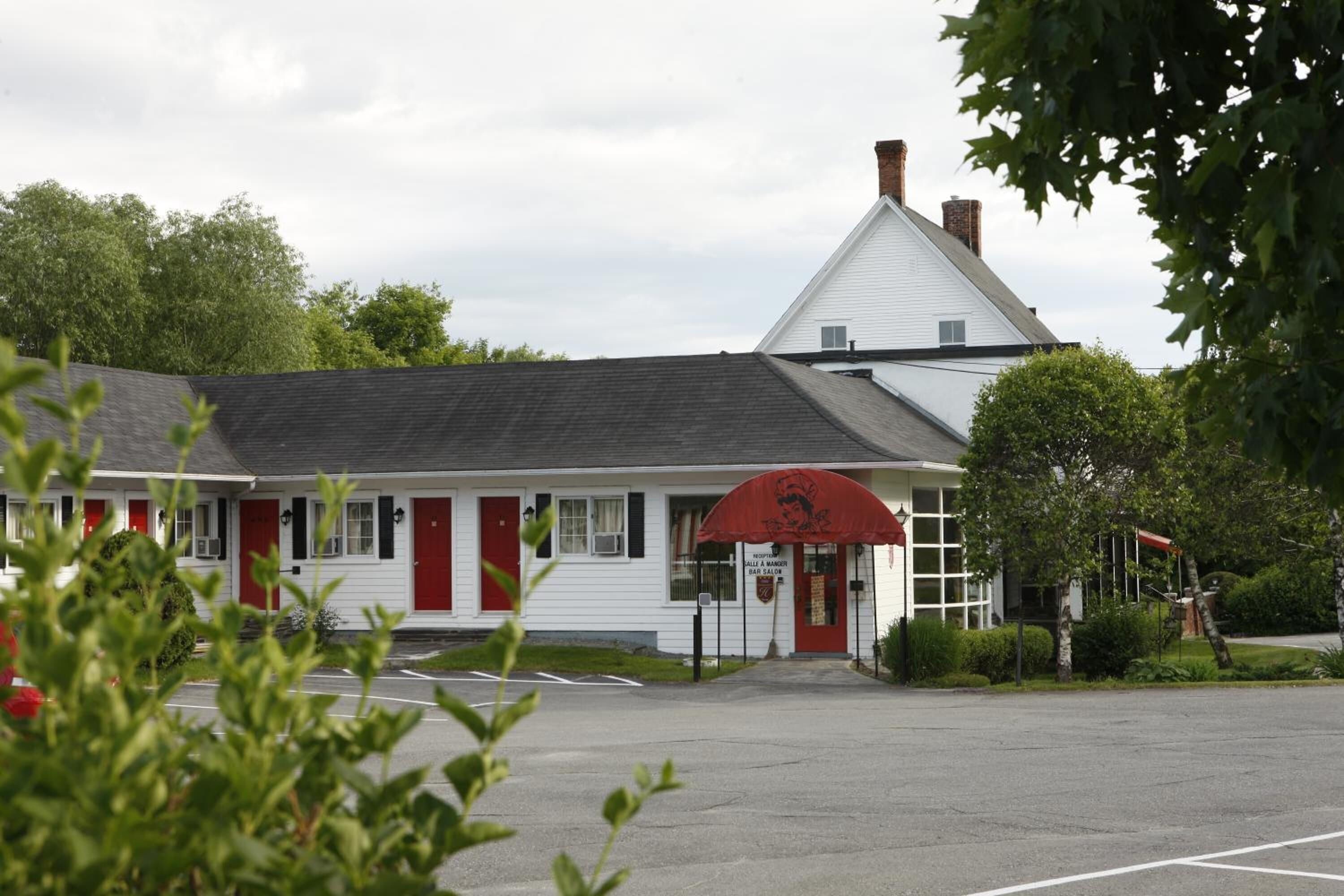 A white building with a red awning and a chimney.