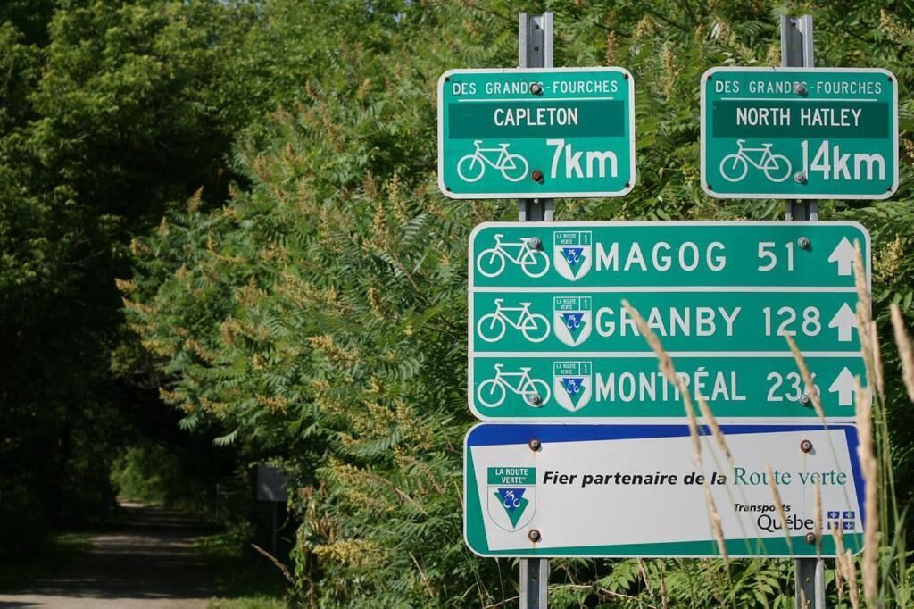 A directional sign with cycling routes to Capleton, North Hatley, Magog, Granby, and Montreal.