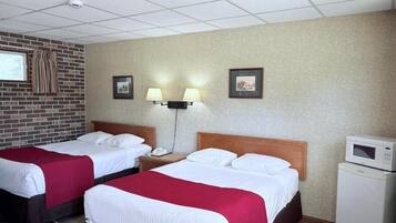 A hotel room with two beds, a brick wall, a microwave, and a small refrigerator.