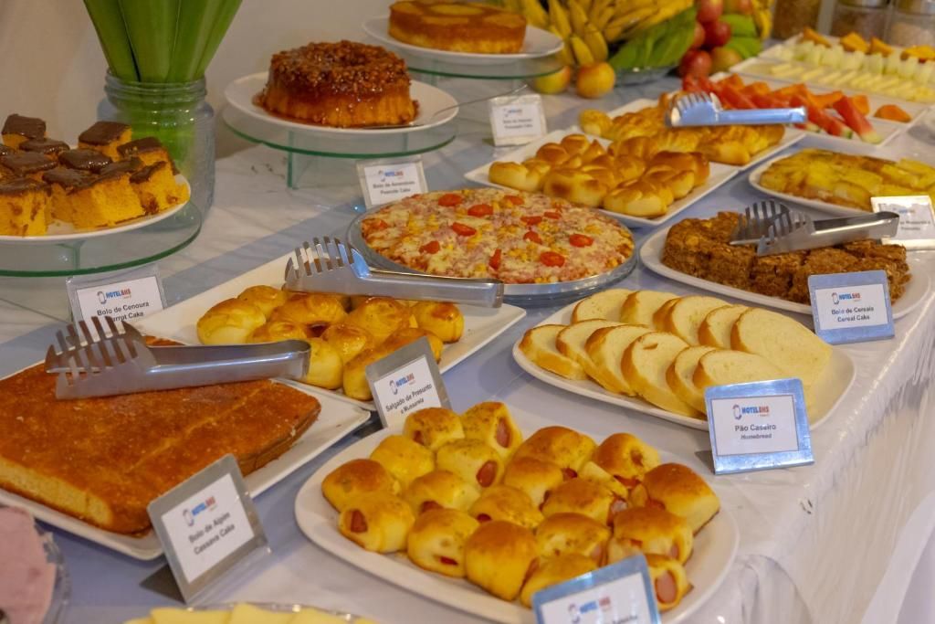 Un bufé con diferentes opciones de comida, incluyendo pasteles, bollos y pizza.