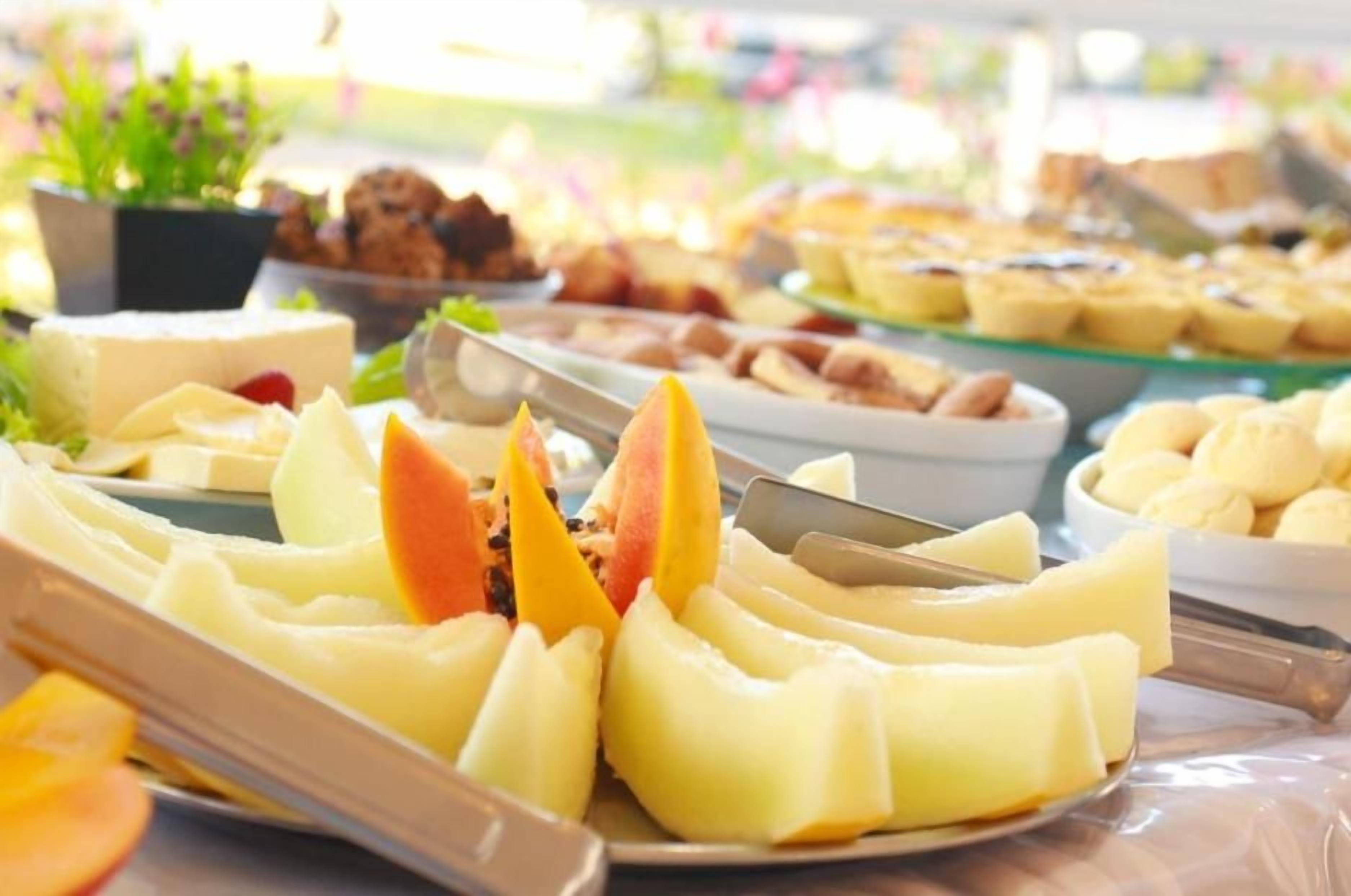 Een buffet met diverse gerechten, waaronder fruit en gebak.