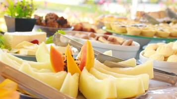 Een buffet met diverse gerechten, waaronder fruit en gebak.