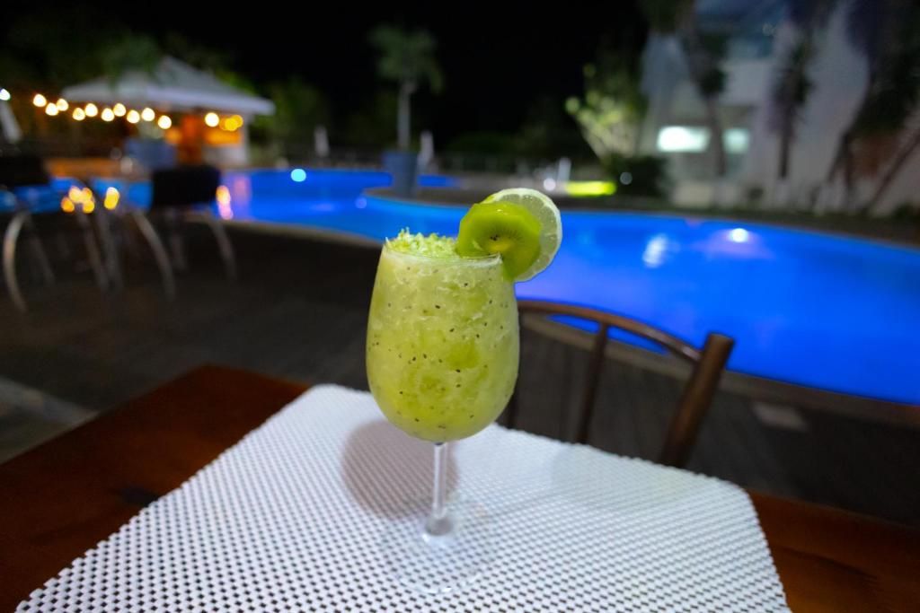 A cocktail glass with a lime garnish on a table by a poolside.