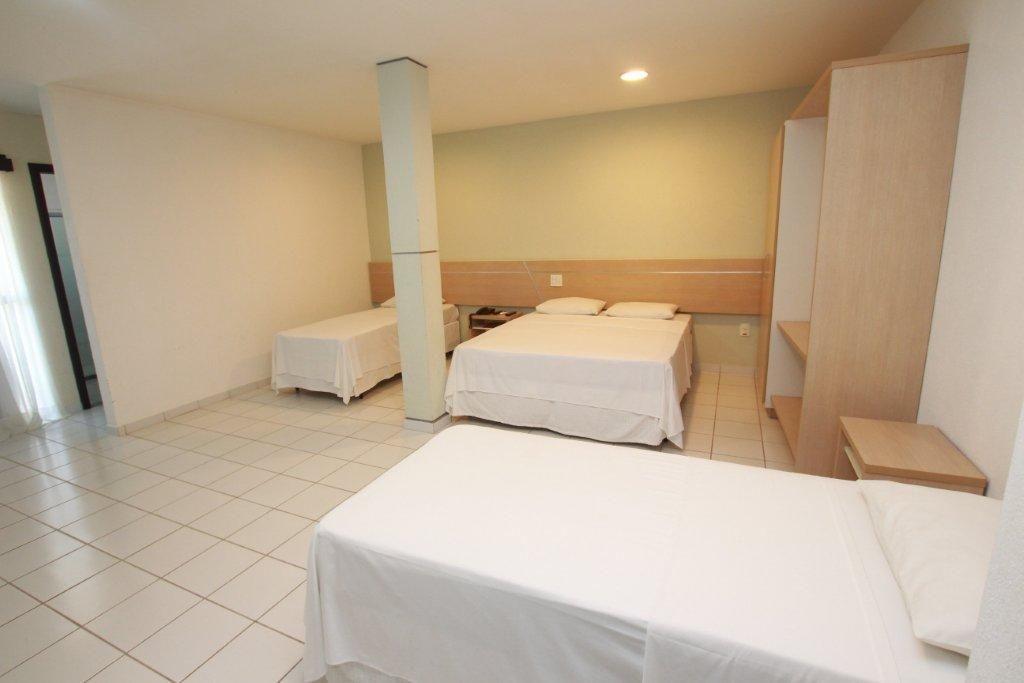 Une chambre d’hôtel avec deux lits, une tête de lit en bois, une petite table et une armoire.