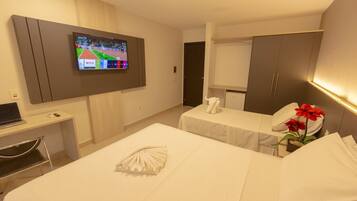 A hotel room with a bed, a desk with a laptop, a TV mounted on the wall, and a closet.