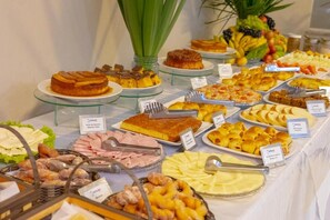 A buffet with various food items including cakes, pastries, and fruits. - Hotel BHS (Linhares)