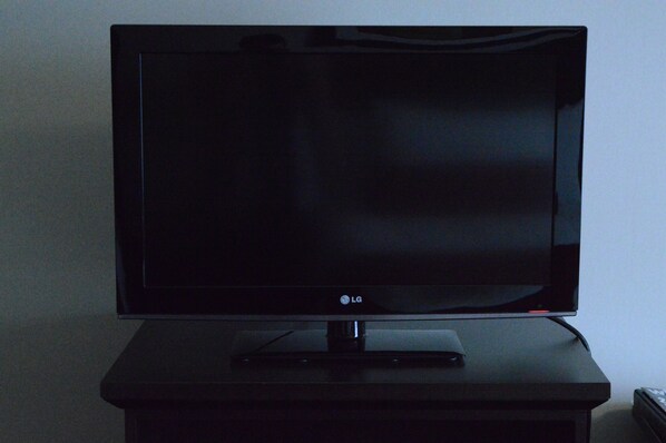 Un televisor LG plano de pantalla negra sobre un pedestal negro en una habitación.