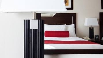 A hotel room with a bed, a bedside table with a lamp, and a wall-mounted picture.