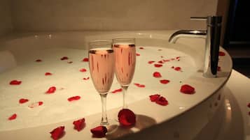 Una bañera con pétalos de rosa y dos copas de champán.