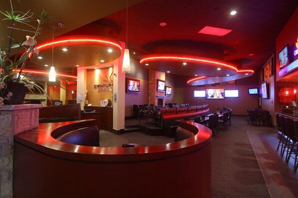 Un restaurante con una barra curva, varias zonas de estar y una iluminación ambiental roja.