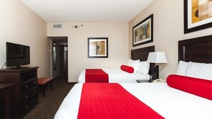 Una habitación de hotel con dos camas, televisión, escritorio y silla.