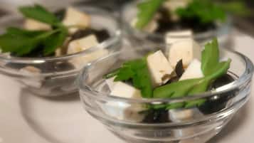 A series of clear glass bowls containing cubes of cheese and green herbs.