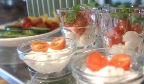 A tray with various food items including bowls of creamy substance with tomato slices, a plate with sliced vegetables, and a glass with a red substance. - Central-Hotel Tegel (Berlin)