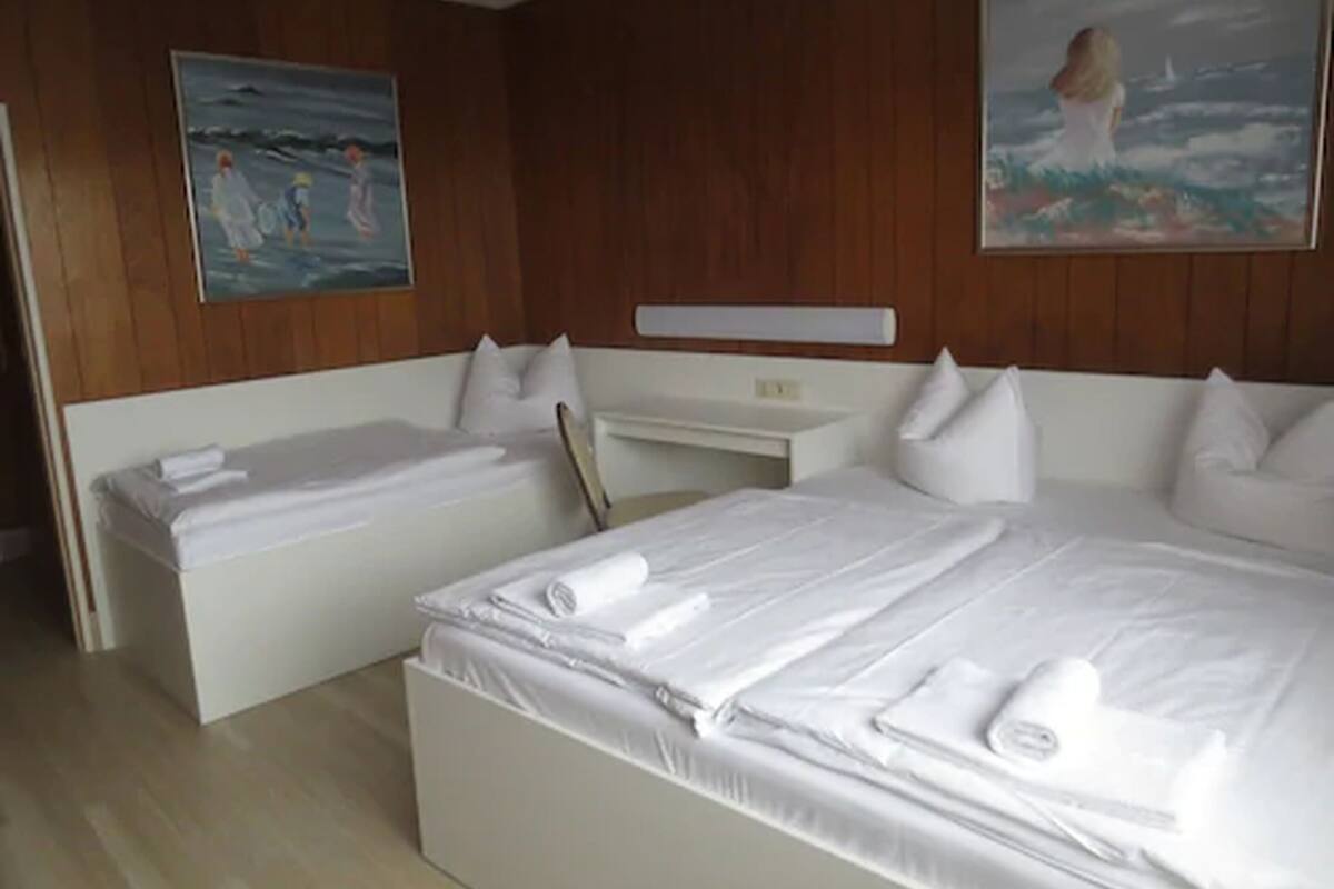 Ein Hotelzimmer mit zwei Betten, einem Schreibtisch und Holzvertäfelung.