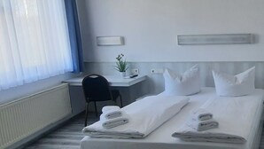 A hotel room with two beds, a desk, a chair, and a potted plant. - Central-Hotel Tegel (Berlin)