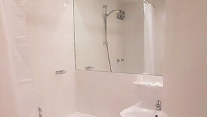 A bathroom with a bathtub, a sink, and a shower. - Central-Hotel Tegel (Berlin)