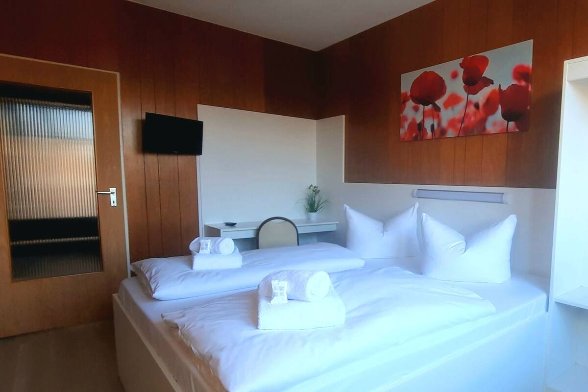 Ein Hotelzimmer mit Bett, Kleiderschrank, Fernseher und einem Gemälde an der Wand.