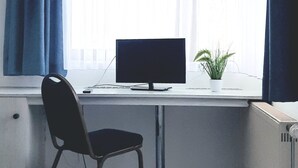 A hotel room with a bed, a desk with a computer, a chair, and a window with curtains. - Central-Hotel Tegel (Berlin)