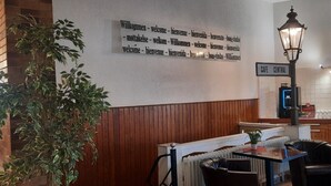 A cafe area with a wooden bench, a table, and a sign indicating 'CAFE CENTRAL'. - Central-Hotel Tegel (Berlin)