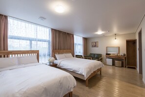 A hotel room with two beds, a desk, a chair, a small trash bin, and a mirror. - Hotel Elin (Jeju City)