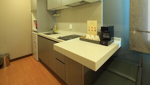 Een moderne keuken met een ingebouwde kookplaat, een koffiezetapparaat en een prullenbak.