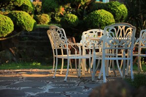 A table and chairs set outdoors with a stone pathway leading to it. - Amber House (Jeju City)