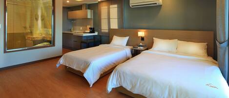 Habitación de hotel con dos camas, kitchenette y aire acondicionado.