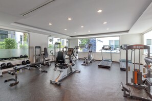 A modern gym with various exercise equipment, large windows, and a view of the outside. - The Regent Residence Kamala (Kamala)