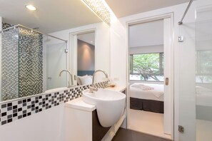 A modern bathroom with a large mirror, a white sink, and a shower area. - The Regent Residence Kamala (Kamala)
