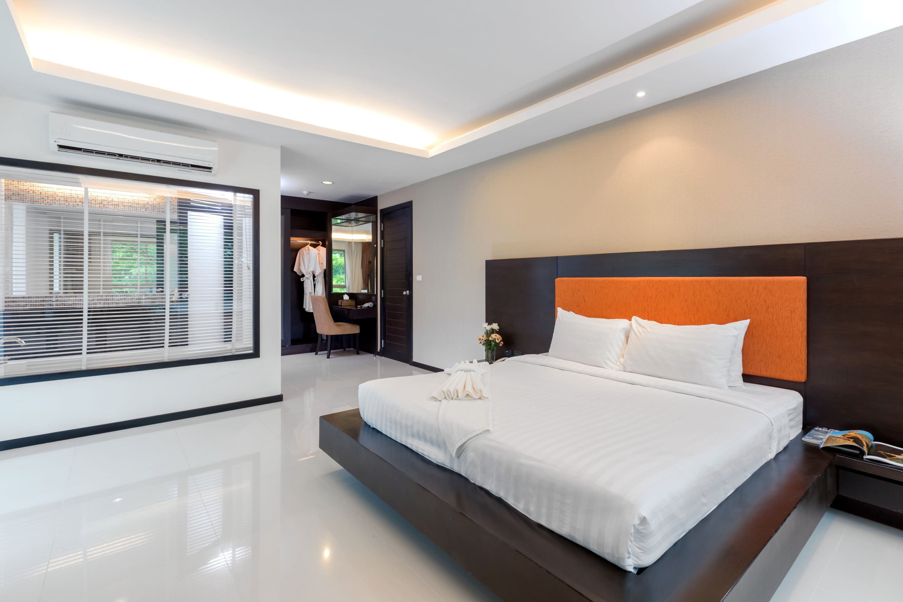 A modern hotel room with a large bed, a desk, and a wardrobe.