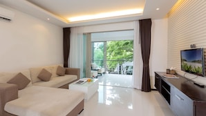 A modern living room with a sofa, coffee table, and TV stand. - The Regent Residence Kamala (Kamala)