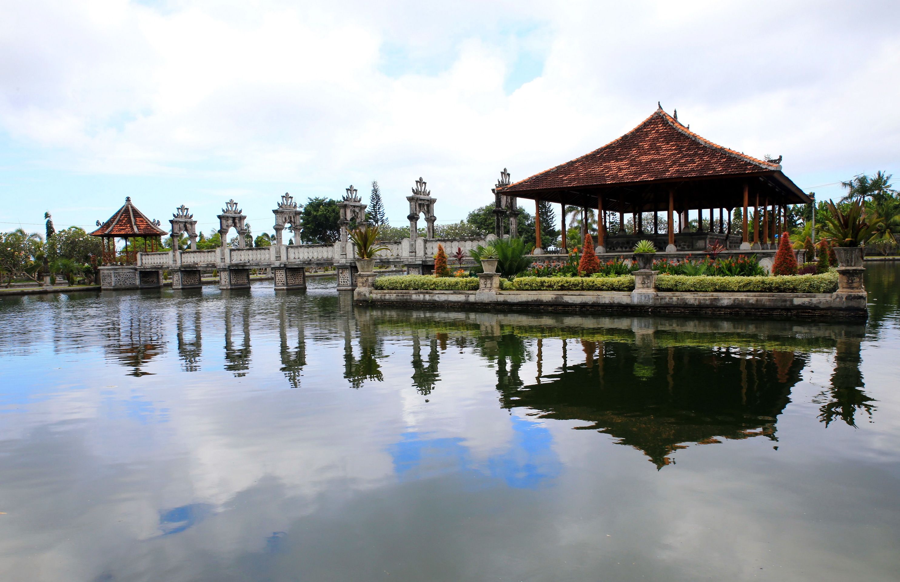 A serene water body with a traditional pavilion and ornate structures in the background.