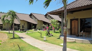A row of houses with tiled roofs, a paved pathway, and small palm trees. - Hotel Uyah Amed & Spa Resort (Karangasem)