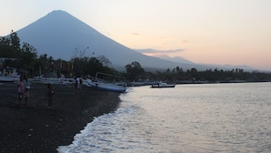 A beach with boats and a mountain in the background. - Hotel Uyah Amed & Spa Resort (Karangasem)