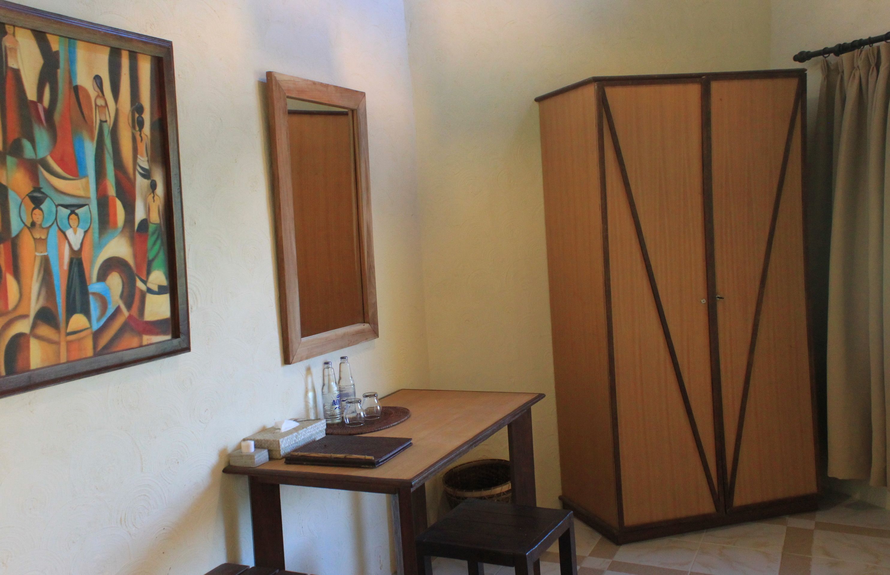 Une pièce comprenant un bureau, un miroir, une armoire et un tableau au mur.