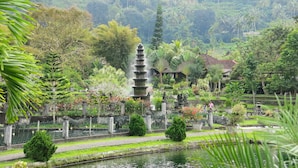 A serene garden with a tiered water fountain, lush greenery, and traditional architecture. - Hotel Uyah Amed & Spa Resort (Karangasem)