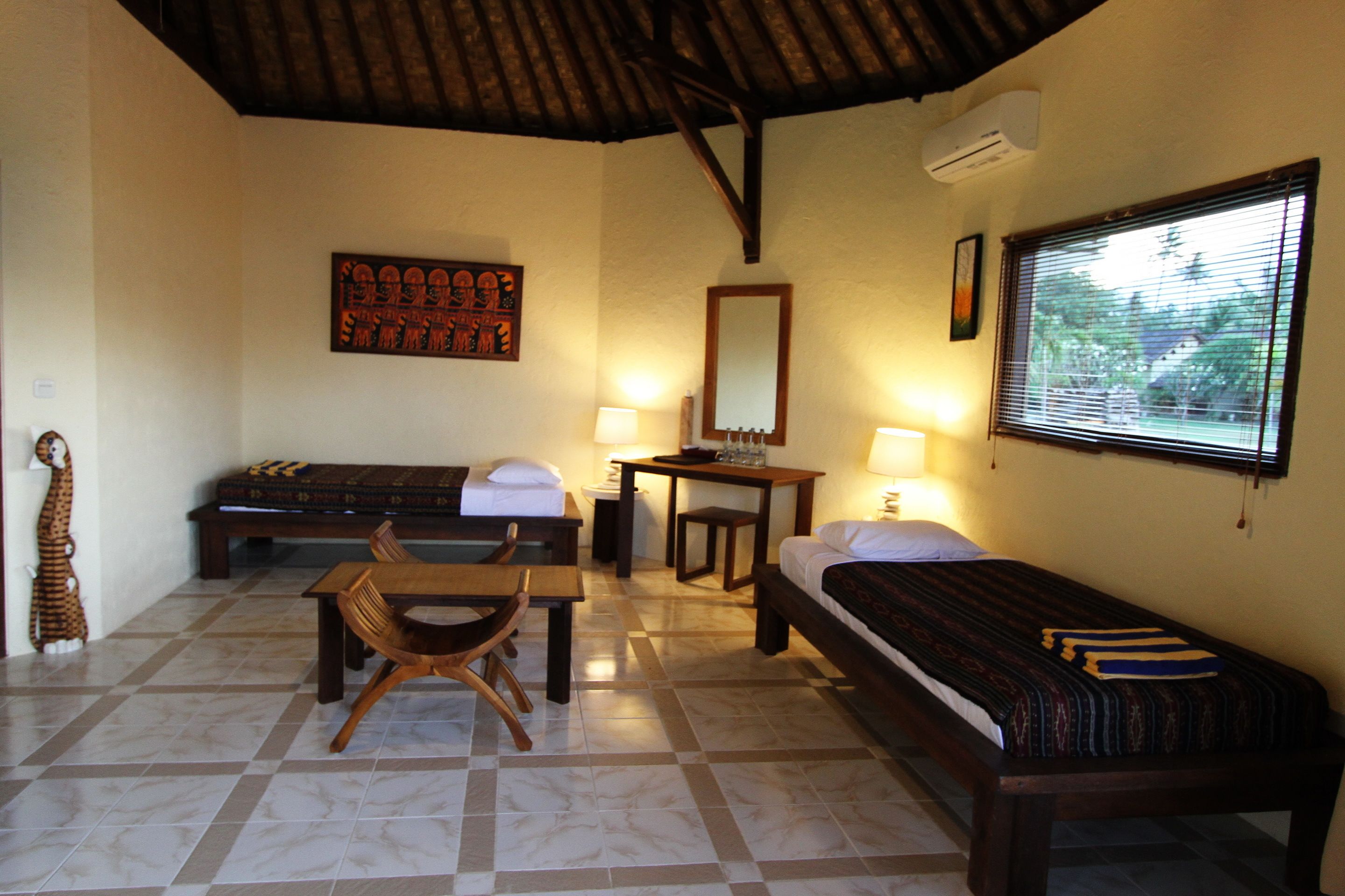 A room with a bed, a desk, a chair, a table, a mirror, and a window.