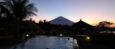 A swimming pool at dusk with a mountain in the background.