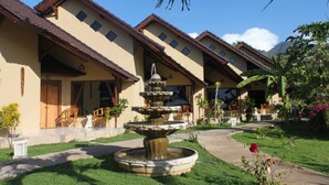 A courtyard with a multi-tiered fountain, outdoor seating, and a mountain backdrop. - Hotel Uyah Amed & Spa Resort (Karangasem)