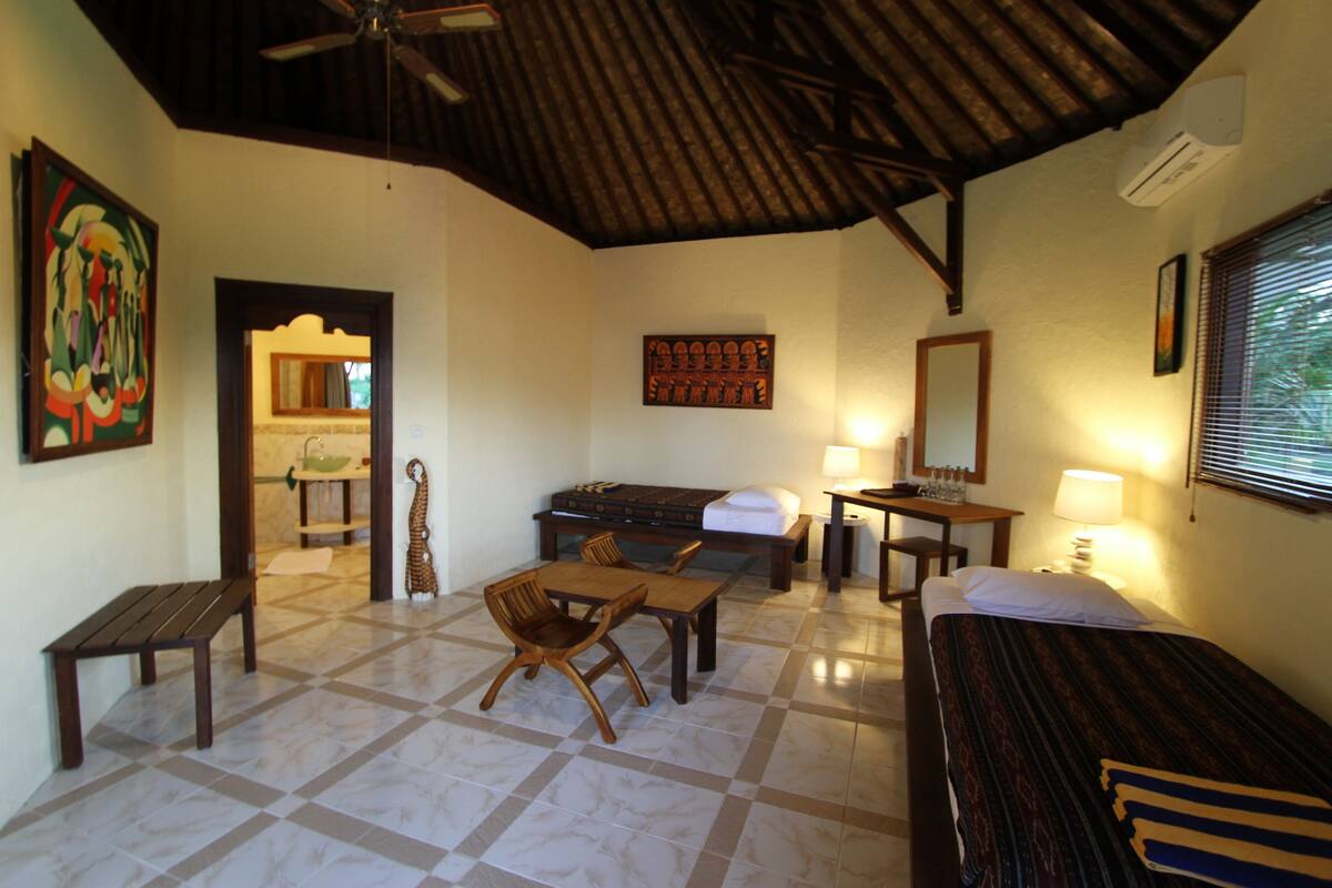A room with a bed, a desk, a chair, a table, and a ceiling fan.