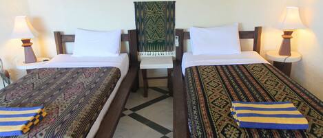 Habitación de hotel con dos camas individuales, una silla y un adorno de pared decorativo.