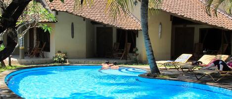 Una piscina con sillas de descanso y palmeras.
