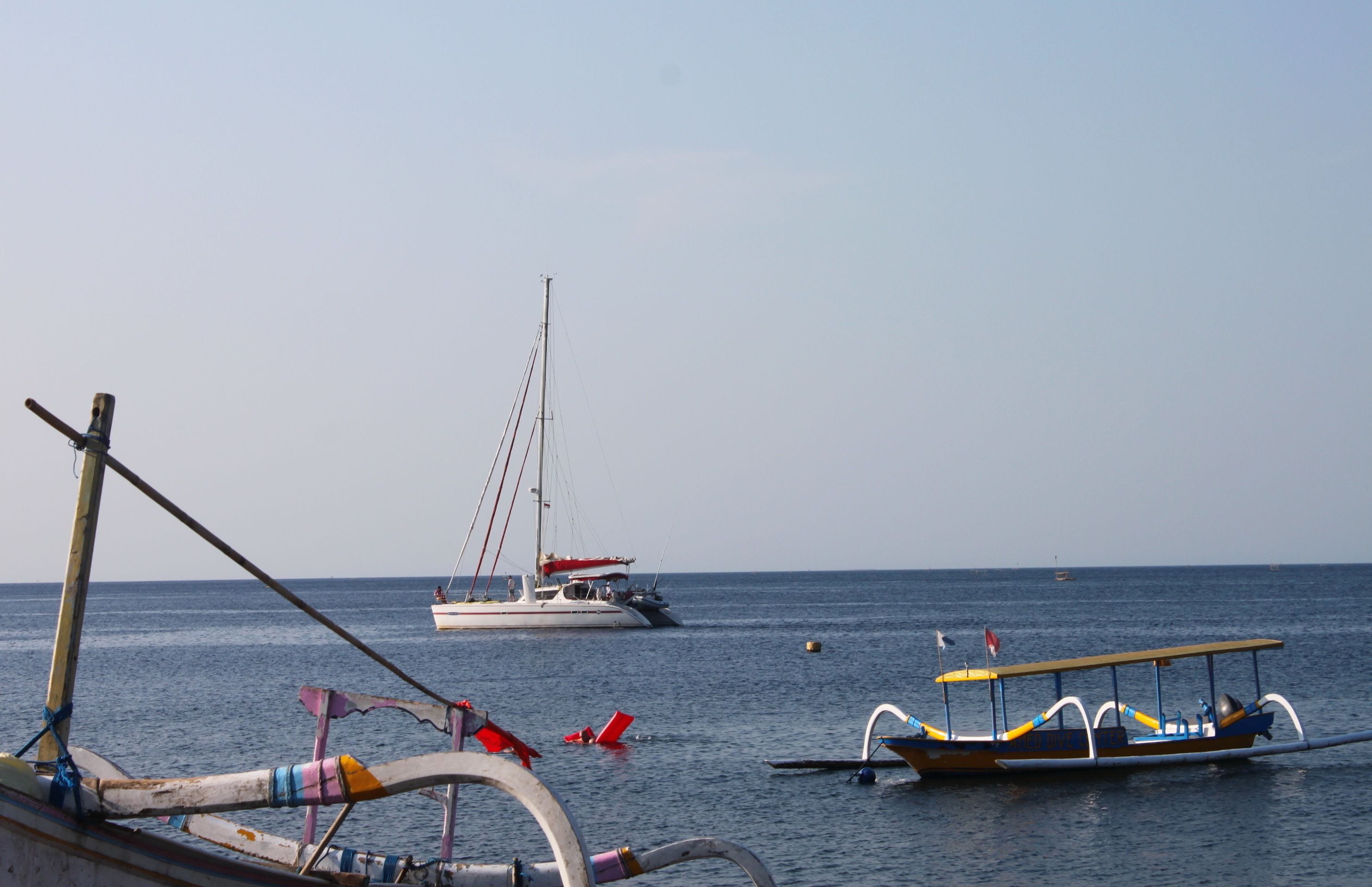 Une scène côtière avec un voilier et un bateau à moteur amarrés près du rivage.