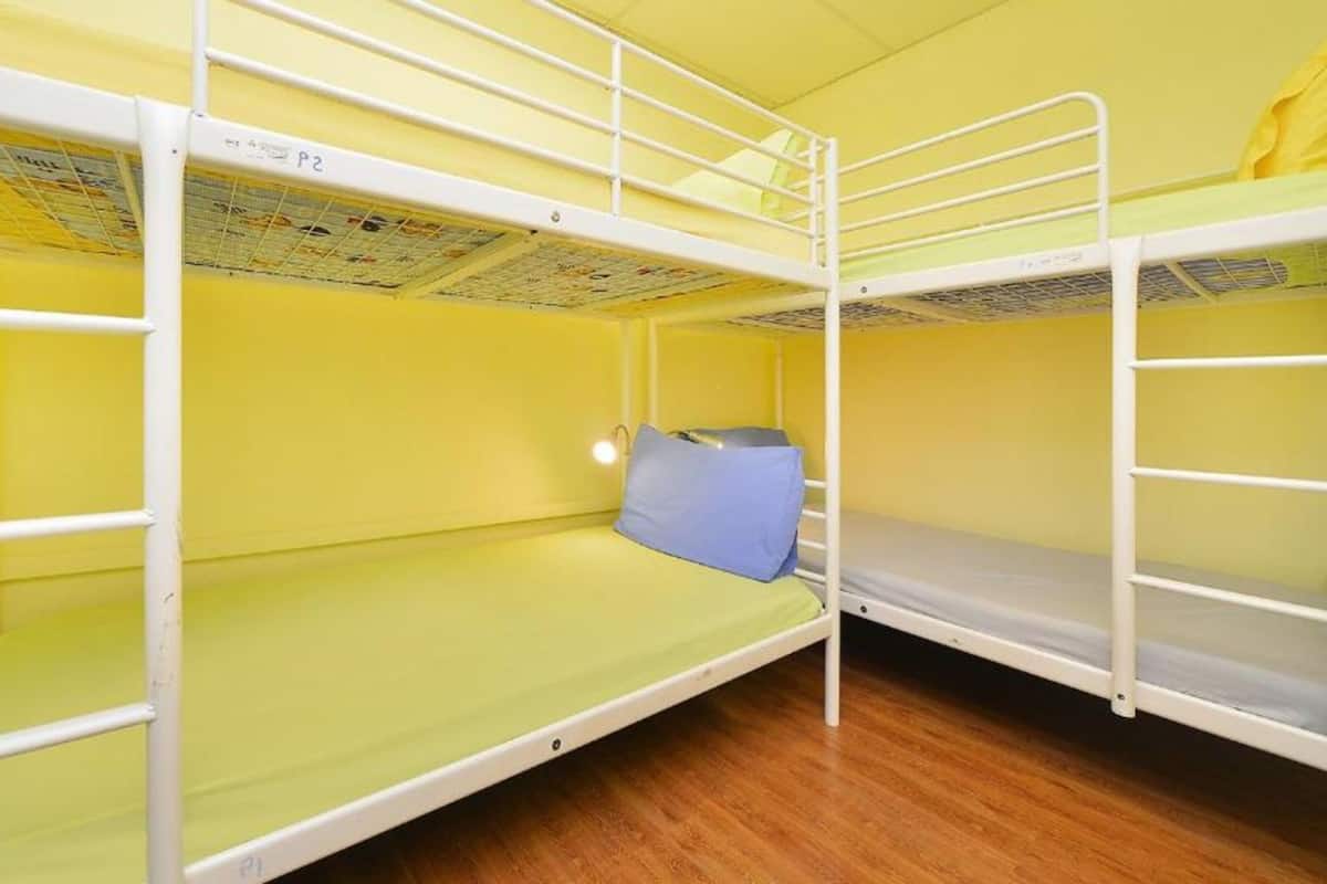 A bunk bed room with yellow walls and a wooden floor.