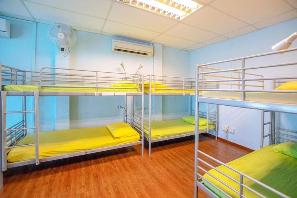 A dormitory room with bunk beds, a ceiling fan, and an air conditioning unit.