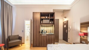 Una habitación de hotel con cama, zona de estar, kitchenette y baño.