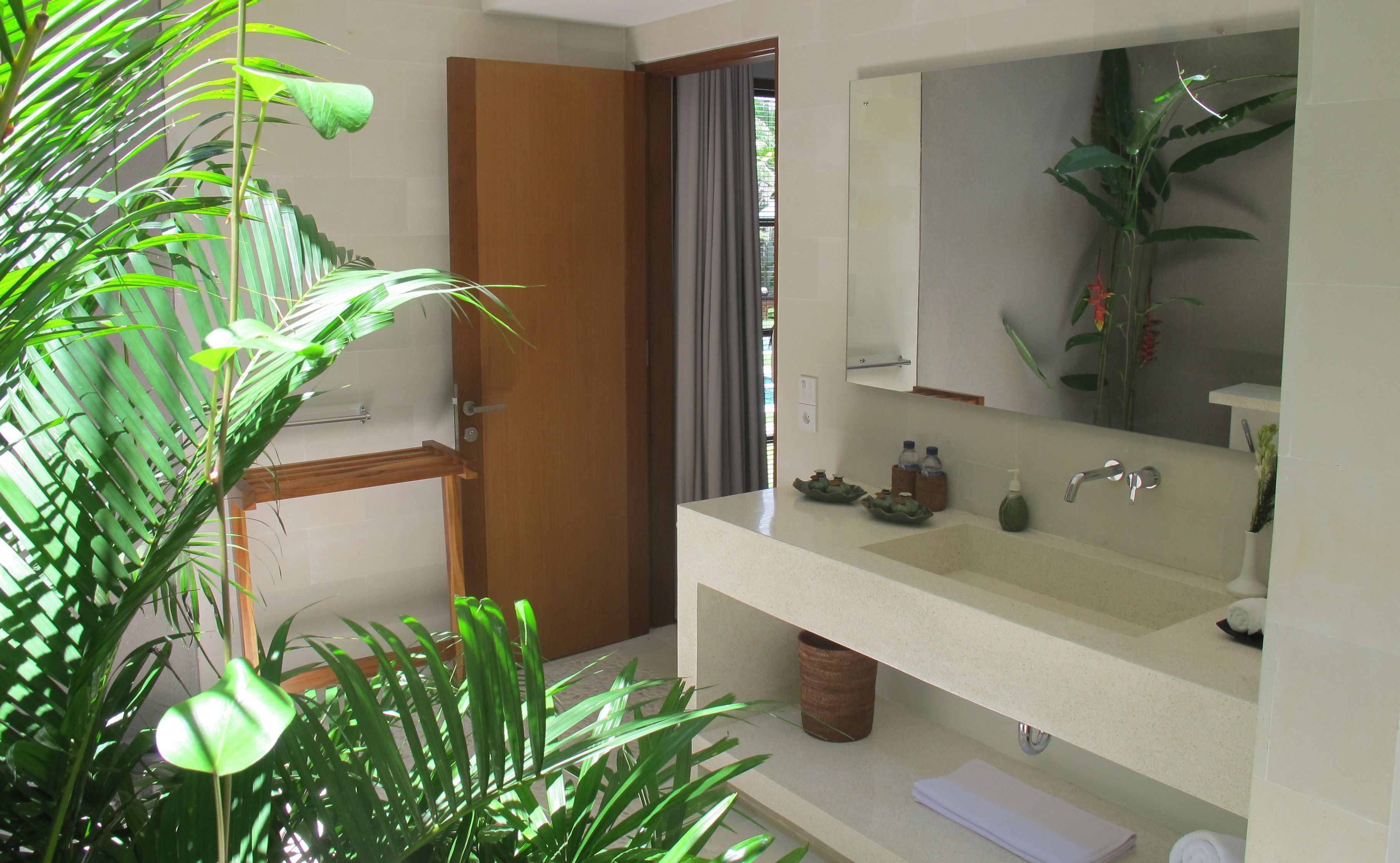 Une salle de bain avec un lavabo, un miroir et une plante en pot.